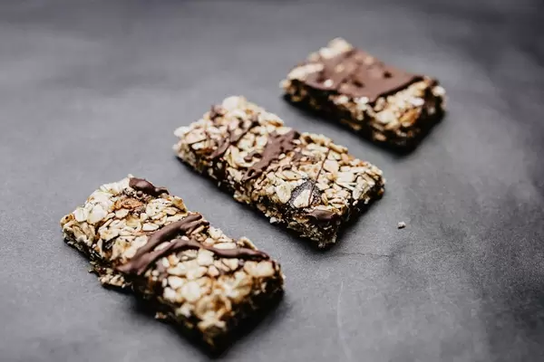 Close up of homemade muesli bars with dates and chocolate. Dark background.
