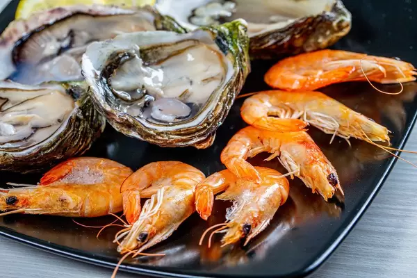 Close-up of king shrimp and oysters on a black plate (Flip 2019)