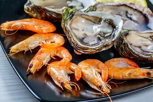 Close-up of king shrimp and oysters on a black plate
