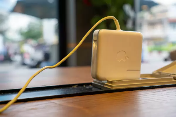 Close Up of Laptop Charger plugged in a Working Desk Power Outlet