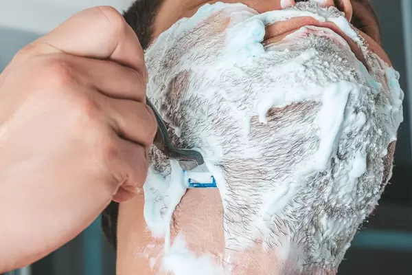 Close up of male shaving with razor