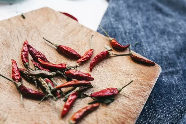 Close up of mini spicy peppers on wooden board.