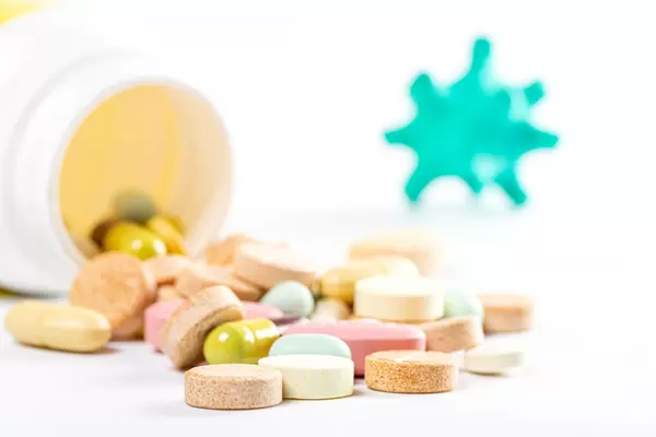 Close-up of multicolored pills with coronavirus model in the background