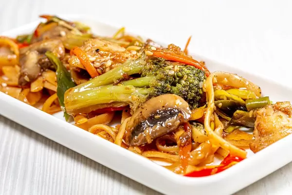 Close-up of noodles with sauce, vegetables and sesame seeds