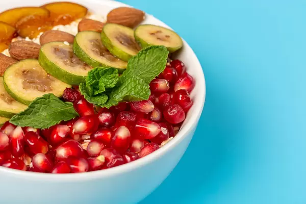 Close-up of oatmeal for breakfast with pomegranate and feijoa on blue background