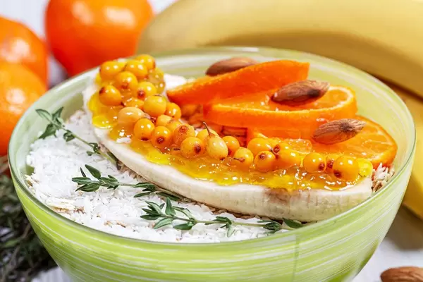 Close-up of oatmeal with fruit, nuts and branches of fresh thyme