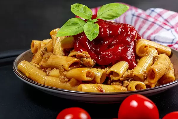 Close-up of pasta with chicken, tomato sauce and basil leaves