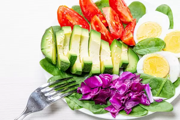 Close-up of pieces of avocado, purple cabbage, tomato with spinach and half boiled eggs (Flip 2019)