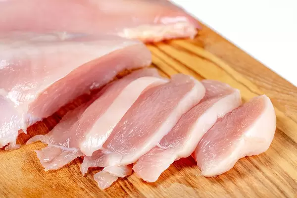 Close up of raw chicken fillet chunks on wooden kitchen board