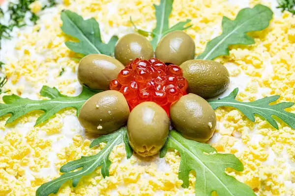 Close-up of red caviar, olives and arugula leaves on top of a salad (Flip 2020)