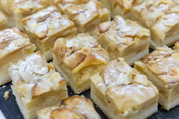Close-up of several pieces of almond-apple cake with icing sugar