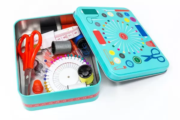 Close-up of sewing utensils such as needles, thread, scissors, measuring tape and thimble in sewing box