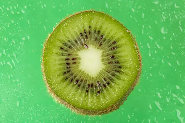 Close-up of sliced kiwi on green background with water drops