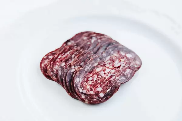 Close up of sliced salami on white background