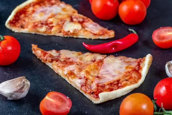 Close-up of slices of meat pizza with cherry tomatoes and chili