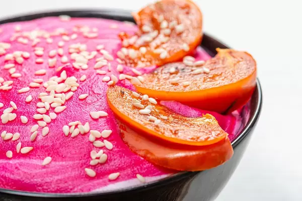 Close-up of slices of persimmon and sesame seeds on pink yogurt. Beautiful oatmeal for Breakfast (Flip 2019)