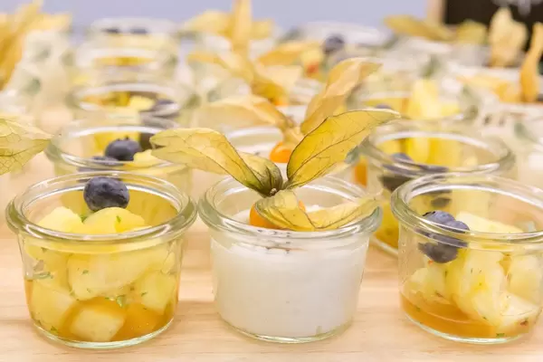Close-up of small breakfast snacks in glasses, with sticky rice, coconut milk, sesame seeds and pickled pineapple in sweet-sour sauce at OMWest19 in Köln