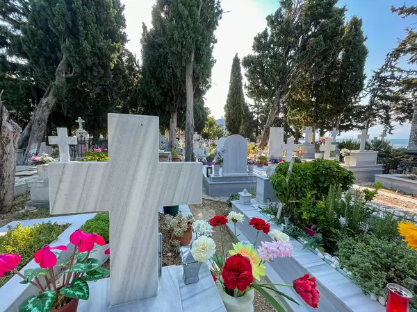 Close-up of stone cross and flowers on a tombstone at the cemetery of Greek island Skiathos