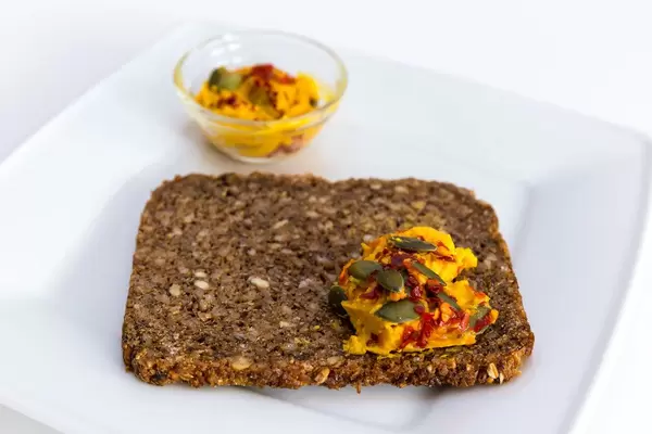 Close-up of sweet potato spread (Süßkartoffelaufstrich) by "Deli Genuss" with wholemeal bread and a small glas bowl on a plate