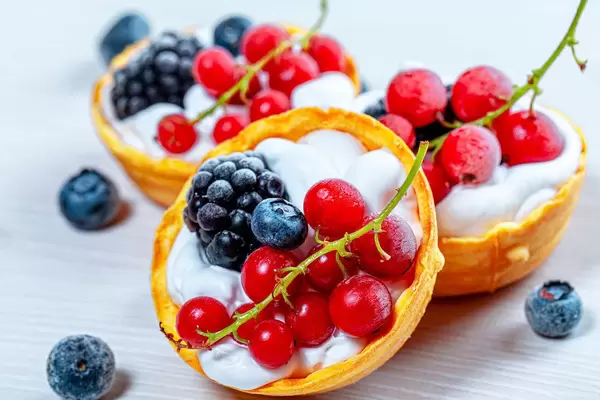 Close-up of tartlets with white cream, red currant, mulberry and blueberry (Flip 2019)