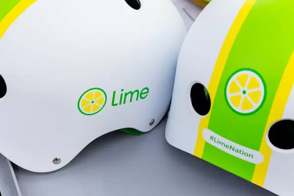 Close-up of the Lime e-scooter logo and #LimeNation hashtag on two white helmets with green and yellow graphics