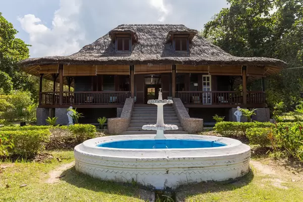 Close-Up of the Plantation House of L'Union Estate with thatched roof and white circular fountain in La Digue