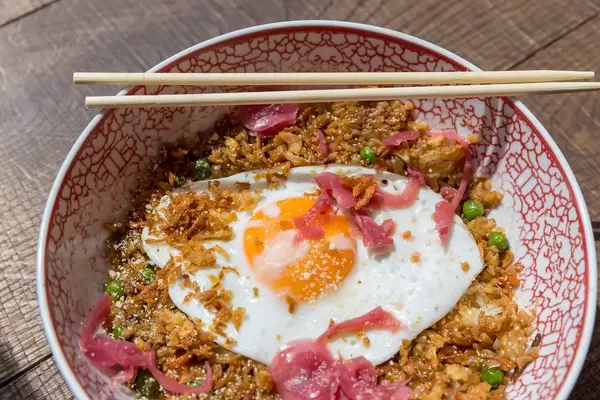 Close-up of the vegetarian Fried Sunrice bowl in Cologne`s coa Wok & Bowls restaurant with fried rice, peas, carrots, onions, garlic and chili