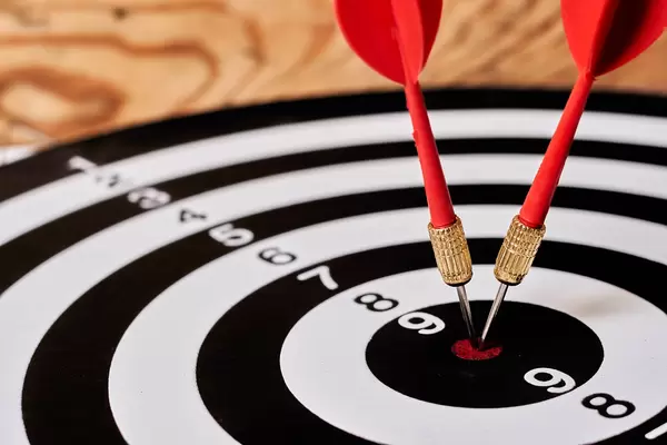 Close-up of two red darts hitting bulls eye