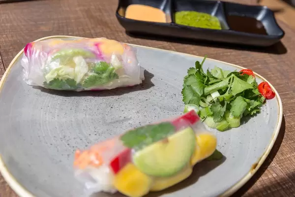 Close-up of vegan summer roles at the coa Wok & Bowls restaurant filled with avocado, mango, pepper, carrots and lettuce