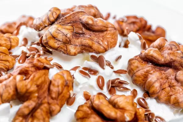 Close-up of walnuts and flax seeds on cottage cheese dessert