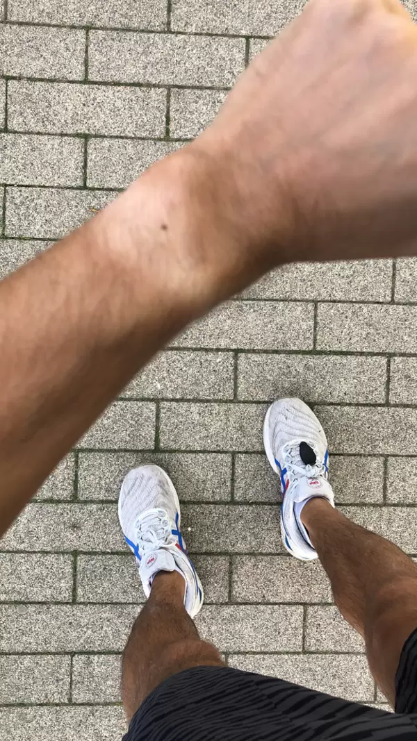 Close-up of watch tan mark on the arm after much exercise. Top view with feet and running shoes