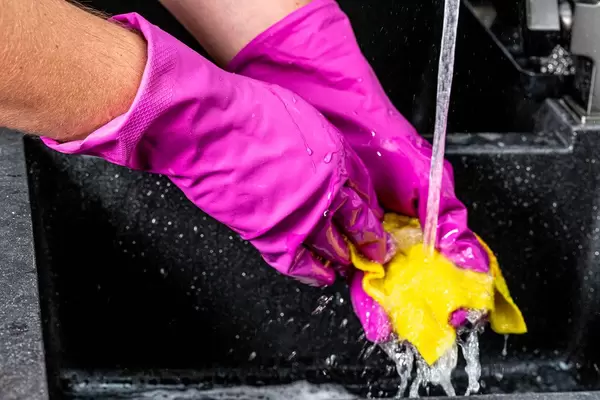Close-up of water flowing from the tap and a man in gloves with a rag