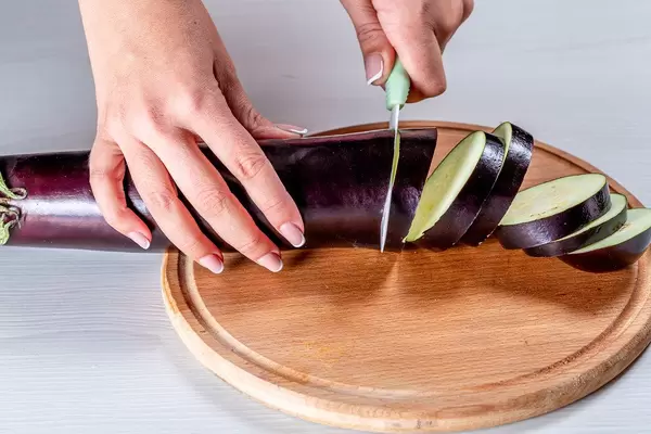 Close-up of woman's hand with knife cuts eggplant (Flip 2019)