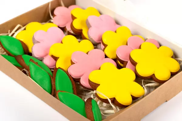 Close-up of yellow and pink gingerbread flowers and green leaves in a cardboard box