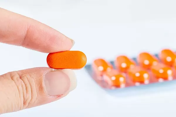 Close-up, orange pill in a woman's hand