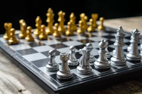 Close Up Photo of a Foldable Travle Chess Board with Silver and Golden Chess Pieces in Starting Position on a Wooden Table