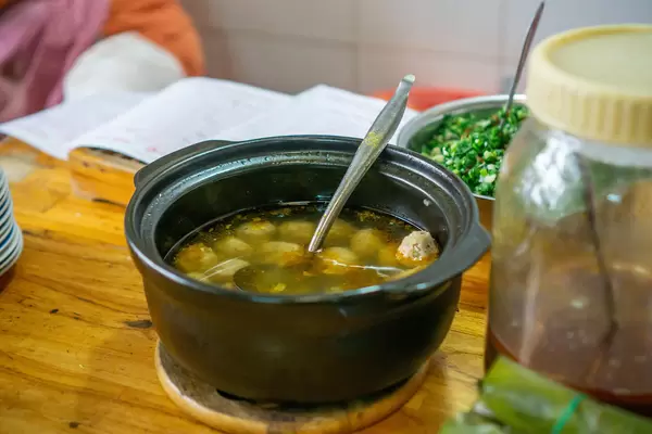 Close Up Photo of Black Clay Pot with Meatball Soup in a Vietnamese Street Food Restaurant
