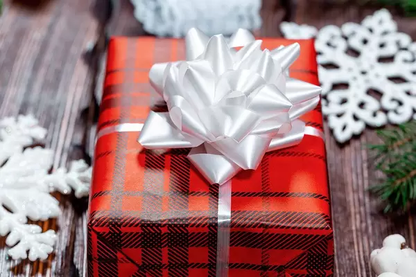 Close Up Photo of Box with Red Gift Wrapping with Christmas Winter Decorations around it