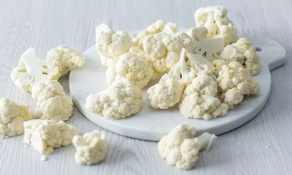 Close Up Photo of Cauliflower on Cutting Board and Wooden Table