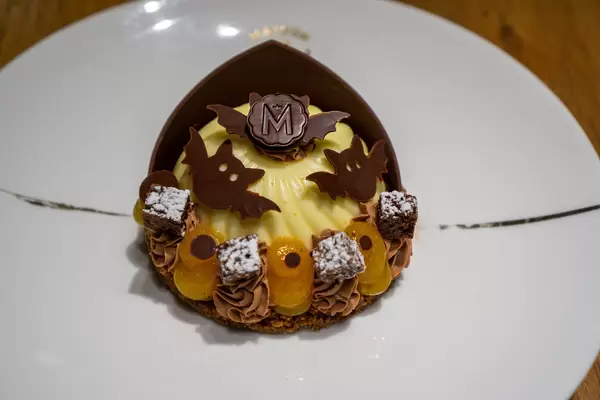Close Up Photo of Cheesecake with Kumquat Creme and Chocolate Decorations in Halloween Design