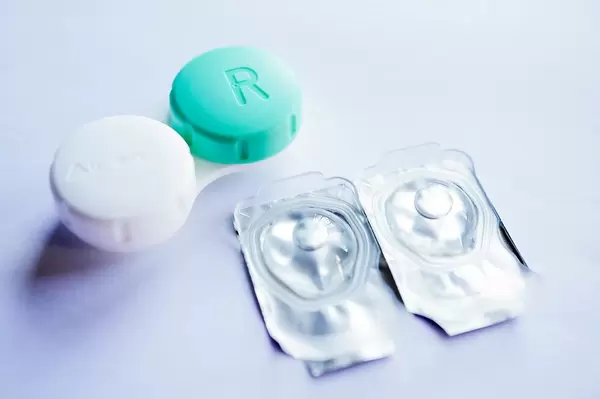 Close Up Photo of Contact Lenses in Packaging and a Container for Contact Lenses on White Background
