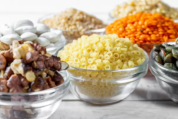 Close Up Photo of Glass Bowls with Healthy Ingredients such as Pasta, Walnuts and Beans and Lentils on Wooden Table
