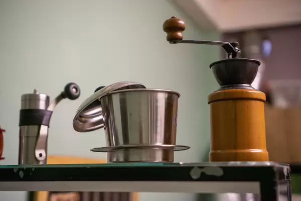 Close Up Photo of Hand Coffee Grinder and a Vietnamese Coffee Filter on a Shelf in a Cafe