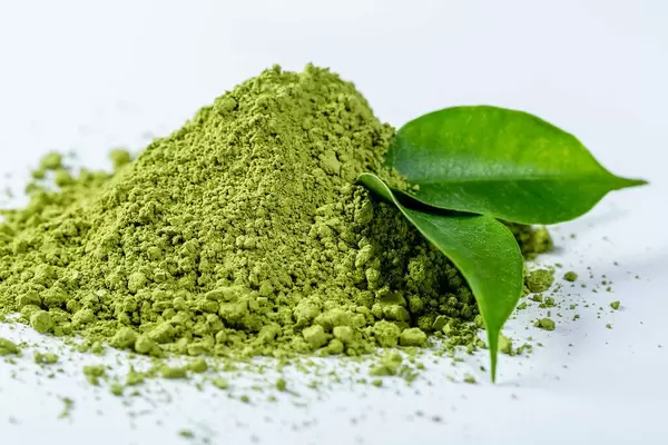 Close Up Photo of Heap of Matcha Powder with Green Tea Leaves on White Background
