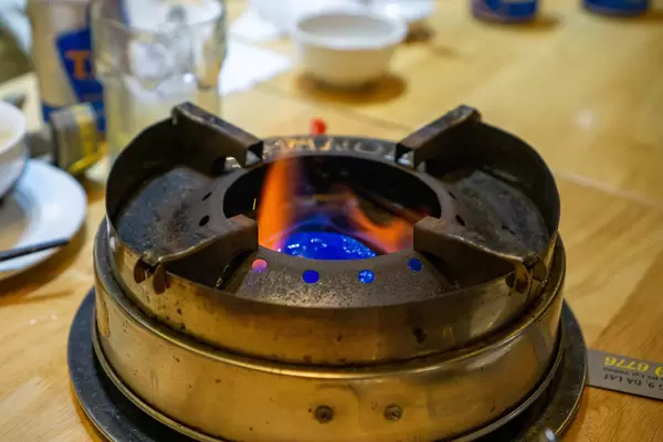 Close Up Photo of Hot Pot Stove with Burning Gel Wax on a Wooden Table in a Restaurant