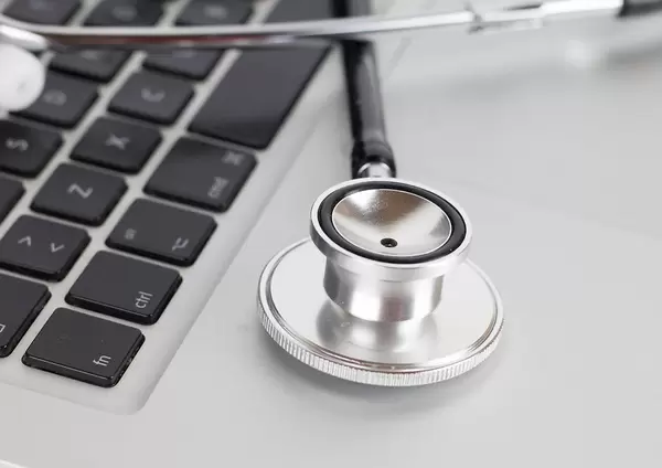 Close Up Photo of Medical Stethoscope laying on Keyboard of Laptop