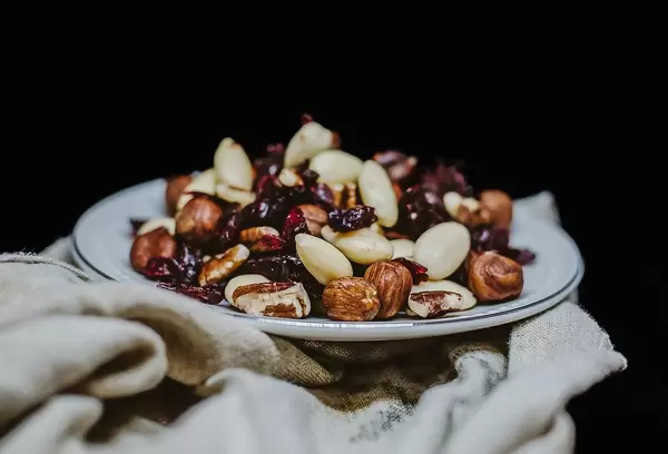 Close Up Photo of Nut Mix with Walnut, Almonds and Raisins on ceramic Plate