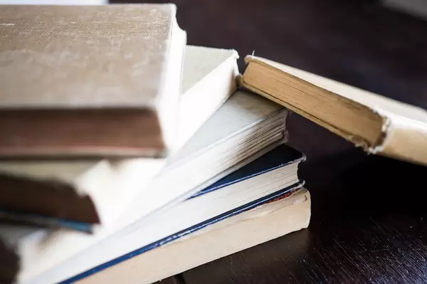 Close Up Photo of Old Books stacked on each other on Black Table