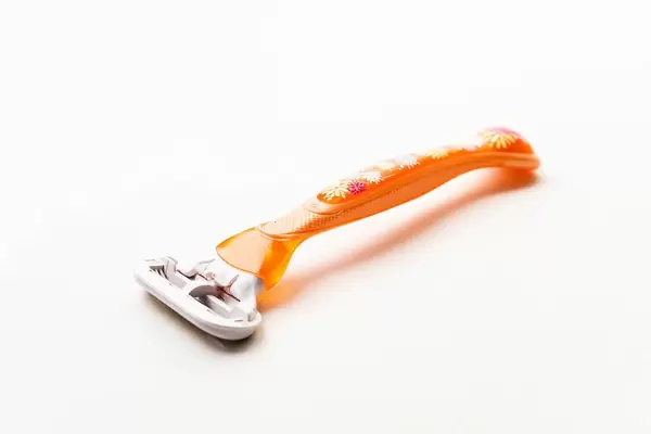 Close Up Photo of Orange Women Shaver on White Background