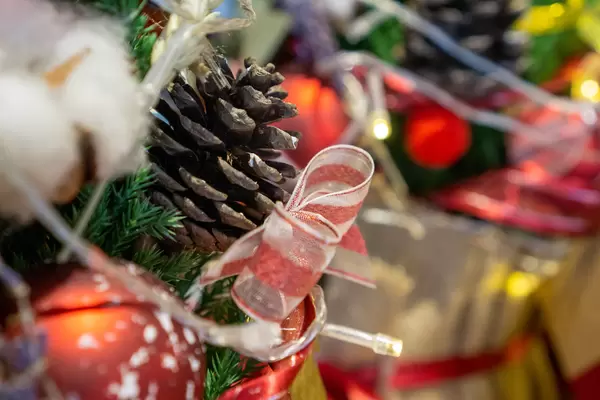 Close Up Photo of Red Ribbon Bow, Christmas Ornament and Fir Cone on a Christmas Tree